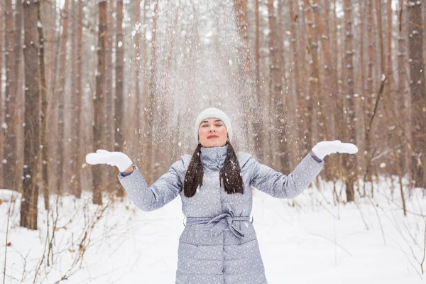 Jeune jolie femme jetant de la neige dans les airs pendant les vacances d'hiver — Photo