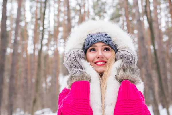 Fashion, winter and people concept - Young attractive woman dressed in fur waistcoat over snowy nature background