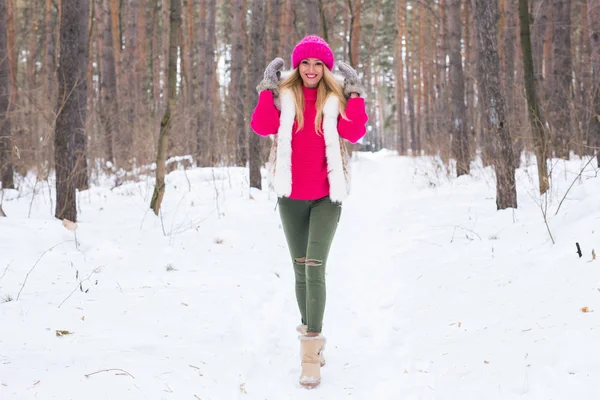 Ομορφιά, τη φύση και άνθρωποι έννοια - όμορφη ξανθιά γυναίκα περπάτημα σε ροζ καπέλο και πουλόβερ χειμώνα ξύλο και χαμογελαστός — Φωτογραφία Αρχείου