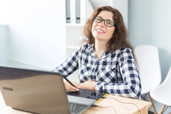 Photography and graphic art concept - Graphic designer using her tablet in a bright office.