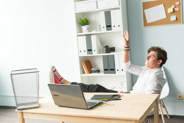 Office, joke, humor, people concept - man sitting at the table with foot on it, chewing the gum and having fun