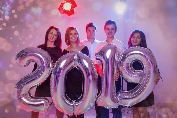 Concetto di festa di Capodanno. Gruppo di giovani amici in possesso di numeri argentati 2019 e lancio di coriandoli — Foto Stock