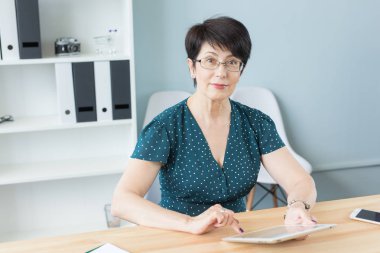 İş ve insan kavramı - orta kendine güvenen kadın ofiste tablet ile çalışma yaşında