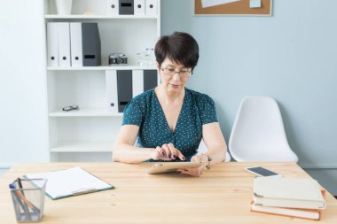 İş, teknoloji ve insan kavramı - ofis ve kullanımı bir tablet oturan ciddi bir kadın