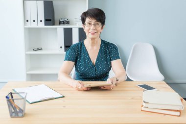 Office, iş, teknoloji ve insan kavramı - güzel orta portre onun el dijital tablet tutarak ve online çalışma ofisinde oturan kadın yaşlı.