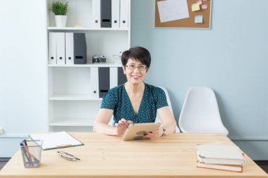 İş, teknoloji ve insan kavramı - orta yaşlı kadın oturup tablo ve kullanımı bir tablet