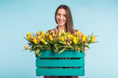 Lale mavi zemin üzerine kutusuyla tutan mutlu beyaz genç kadın