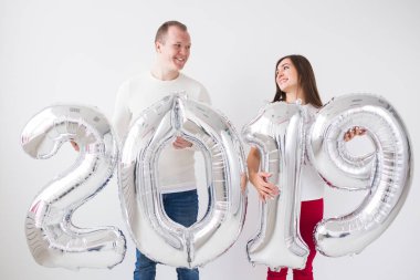 Yeni yıl, kutlama ve tatil kavramı - beyaz Oda arka planda yeni yıl için gümüş balon işareti 2019 tutan sürpriz aşk çift yaptı