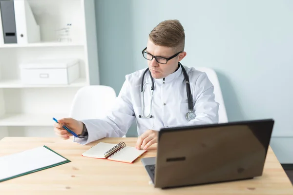 Koncepcja medycyna, pracy i osób - przystojny lekarz siedzi przy stole i pisania przepis — Zdjęcie stockowe
