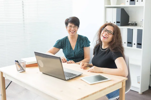 Zwei glückliche Geschäftsfrauen, die im Büro zusammenarbeiten — Stockfoto