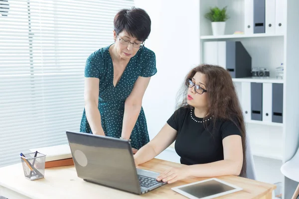 Geschäftsleute, Technik und Kommunikationskonzept - Dame mittleren Alters hilft ihrer Kollegin mit Laptop — Stockfoto