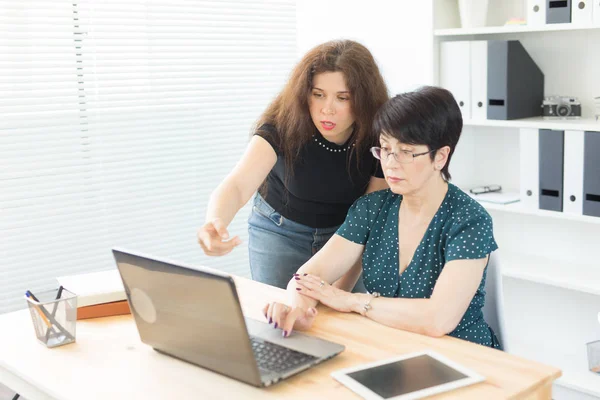 Tecnologia, business, insegnamento e concetto di persone - donna spiegare qualcosa al computer portatile un'altra donna — Foto Stock