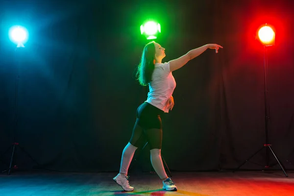 Concepto de danza moderna, deporte y gente: mujer joven bailando jazz funk en la oscuridad bajo una luz colorida — Foto de Stock