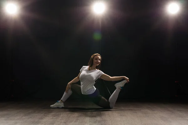 Mujer joven bailarina gimnasia ejercicio pose sobre fondo oscuro — Foto de Stock