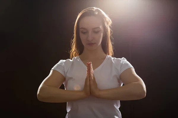 Emotionen, Gefühle und Menschenkonzept - Nahaufnahme einer jungen Frau, die im Dunkeln unter dem Licht betet — Stockfoto