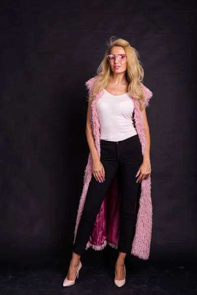 Concepto de moda y belleza - Hermosa mujer rubia vestida con camisa blanca y cárdigan rosa sobre fondo oscuro —  Fotos de Stock