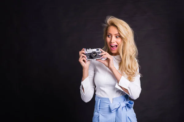 Conceito de lazer e hobby - Mulher loira encantadora excitada com câmera no fundo preto com espaço de cópia — Fotografia de Stock