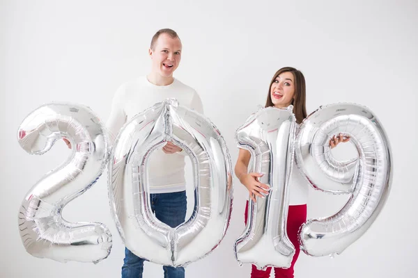 Novo 2019 Ano está chegando conceito - Jovem alegre e mulher estão segurando números coloridos de prata dentro de casa . — Fotografia de Stock