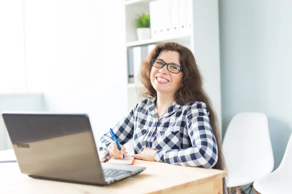 Επιχείρηση και άνθρωποι έννοια - νεαρός χαμογελαστό γυναίκα κάθεται στο γραφείο και την εργασία — Φωτογραφία Αρχείου