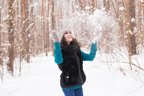 Temporada, lazer e conceito de pessoas - jovem mulher é feliz e jogando neve na natureza de inverno — Fotografia de Stock