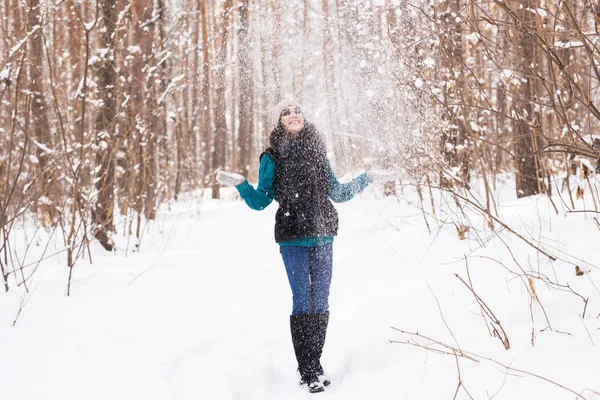 Сезон, дозвілля і концепція людей - молода жінка щаслива і кидає сніг в зимову природу — стокове фото