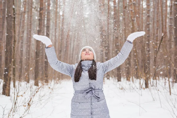 Saison, loisirs et concept de personnes - la jeune femme est heureuse et jette de la neige dans la nature hivernale — Photo