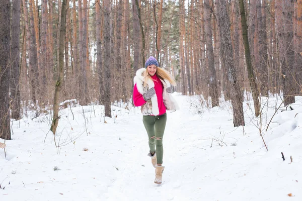 Сезон, природа, концепція людей - красива блондинка, що бігає в зимовому лісі і посміхається — стокове фото