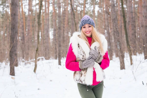 Concepto de moda, invierno y gente - Mujer atractiva joven vestida con chaleco de piel sobre fondo de la naturaleza nevada —  Fotos de Stock