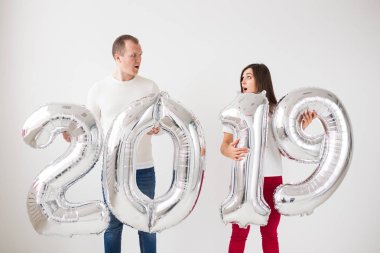 Yeni 2019 yılı önümüzdeki kavramı - mutlu genç adam ve kadın kapalı gümüş renkli numaraları tutuyorsun.