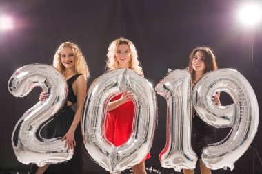 Yeni 2019 yıl geliyor. Grup gümüş renkli numaraları tuttuktan neşeli genç kadını.