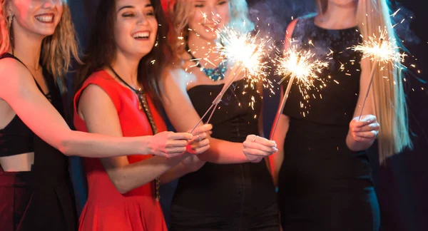 Obchodzi się z zabawy. Grupa wesoły młodych kobiet prowadzących ognie. Nowy rok, święta i koncepcja partii. — Zdjęcie stockowe
