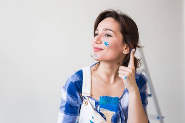 Onarım, yenileme ve insanlar kavramı - genç kadın duvar boyama ve çok mutlu gibi görünüyor o renkli yanak ile