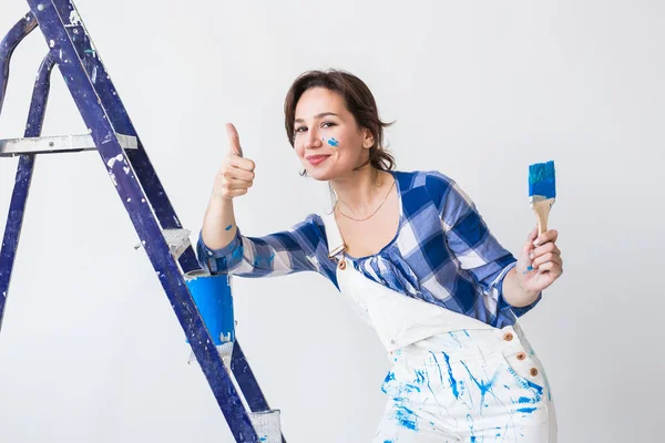 Reparación, renovación, concepto de trabajador y personas - Feliz joven pared de pintura en casa, que nos muestra los pulgares hacia arriba — Foto de Stock