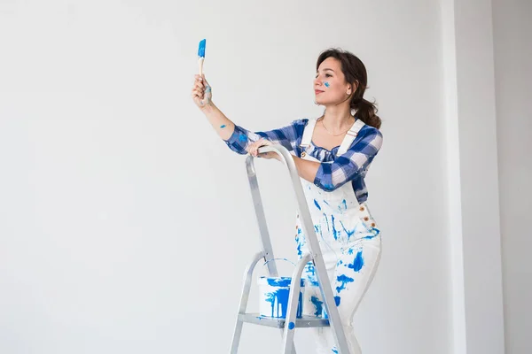 Gente, renovación y concepto de trabajo - Hermosa mujer de pie en la escalera y paredes de pintura — Foto de Stock