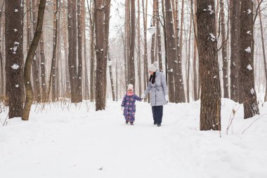 Mutlu aile annesi ve kızı eğleniyor, kış yürüyüşünde dışarıda oynuyorlar.