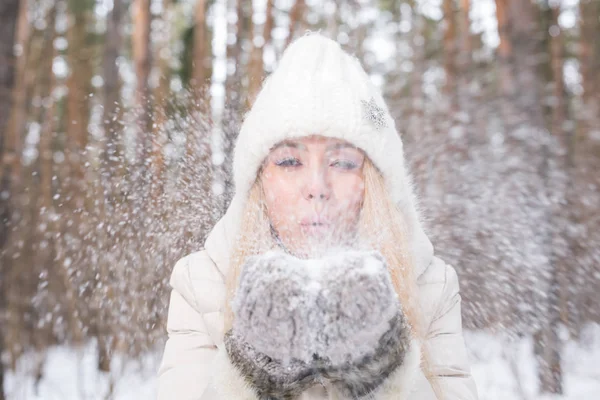 Natale, vacanze e concetto di stagione - Giovane donna bionda felice che soffia neve nella natura invernale — Foto Stock