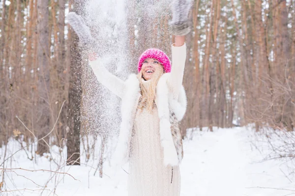 Stagione, svago e concetto di persone: la giovane donna è felice e getta neve nella natura invernale — Foto Stock