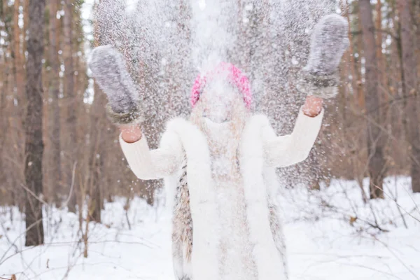 Retrato de una joven arrojando la nieve. Sonriente chica caminando en un parque de invierno y divirtiéndose en un frío día soleado al aire libre — Foto de Stock