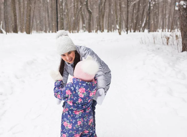 Зима, семья и детство - мама гуляет с маленькой дочкой в заснеженном лесу и обнимается — стоковое фото