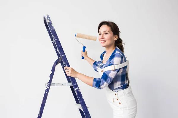 Reparación, renovación, nuevo concepto de hogar y personas - Hermosa mujer pinta la pared durante la redecoración —  Fotos de Stock