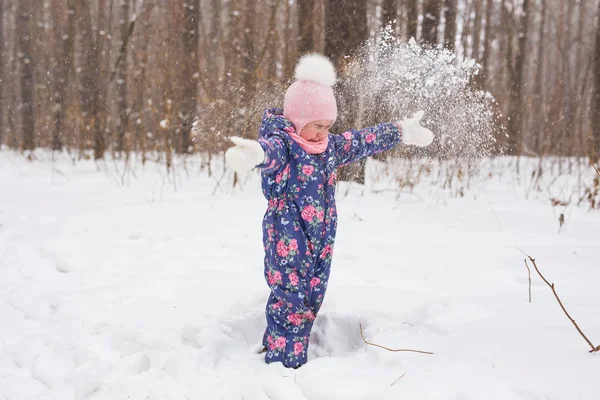 Conceito de infância e pessoas - menina andando no inverno ao ar livre e jogando a neve para cima — Fotografia de Stock