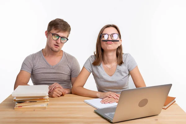 Bildung und Menschen-Konzept - ein paar junge Studenten mit Brille sehen aus, als ob sie gelangweilt wären, Hausaufgaben zu lernen, und machen dumme Witze — Stockfoto