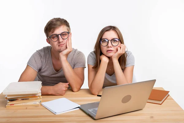 Istruzione e concetto di persone - coppia di giovani con gli occhiali sembrano stufi di imparare a fare i compiti — Foto Stock