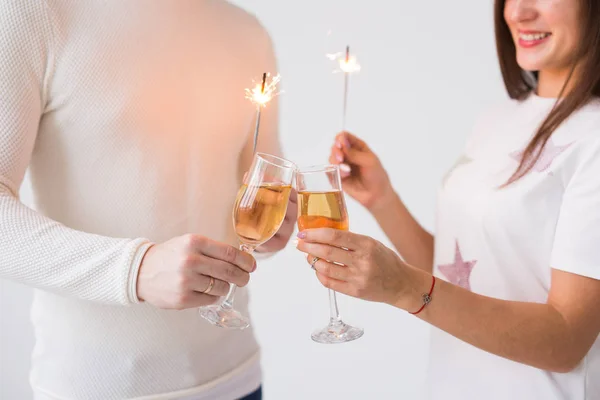 Conceito Dia dos Namorados - Fechar-se de feliz sorrindo alegre casal atraente celebrando com copos de champanhe e faíscas no fundo branco — Fotografia de Stock