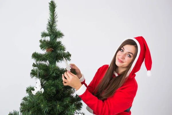 Férias de inverno, xmas e conceito de pessoas - Retrato de bela jovem no chapéu de Santa decoração árvore de Natal em casa em fundo branco — Fotografia de Stock