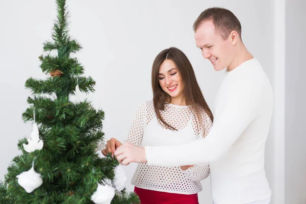 Vacaciones de invierno y el concepto de la gente - pareja amorosa colgando decoraciones en el árbol de Navidad — Foto de Stock