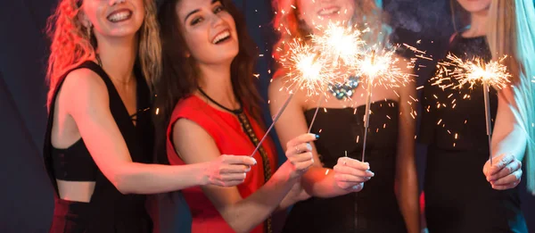 Festa de Ano Novo, celebração e conceito de férias - Jovens mulheres alegres segurando faíscas ardentes — Fotografia de Stock