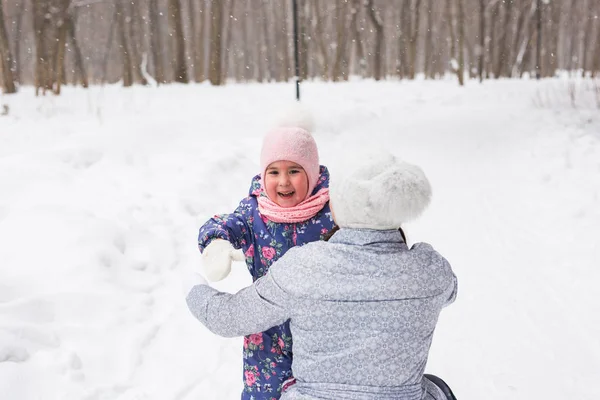 Conceito de família, crianças e natureza - Jovem mãe abraçar pequena criança feliz no parque de inverno — Fotografia de Stock