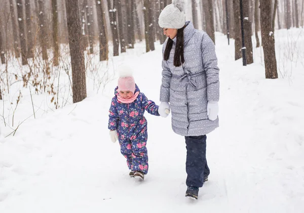 Conceito de inverno, família e pessoas - a mãe está andando com sua filha na floresta de inverno . — Fotografia de Stock