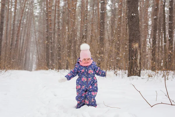 Childhood and nature concept - Adorable child playing in winter park — Stock Photo, Image